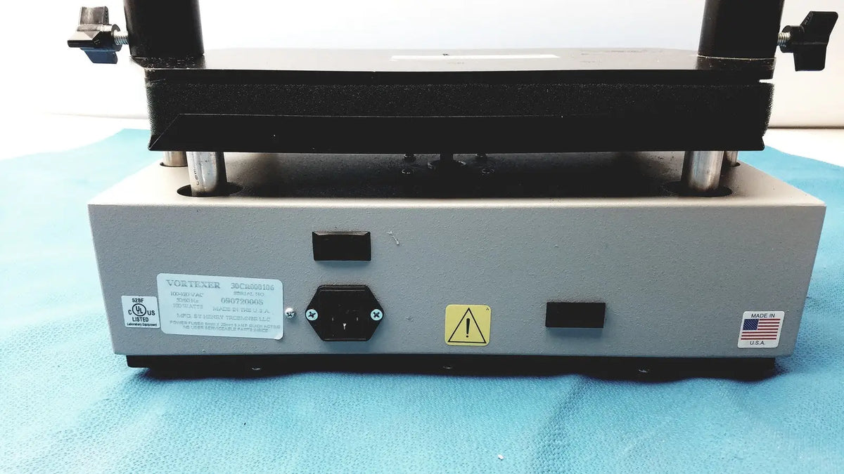 Gray metal industrial press with black top plate and silver legs in tripath imaging multi-vial vortexer 30cr000106