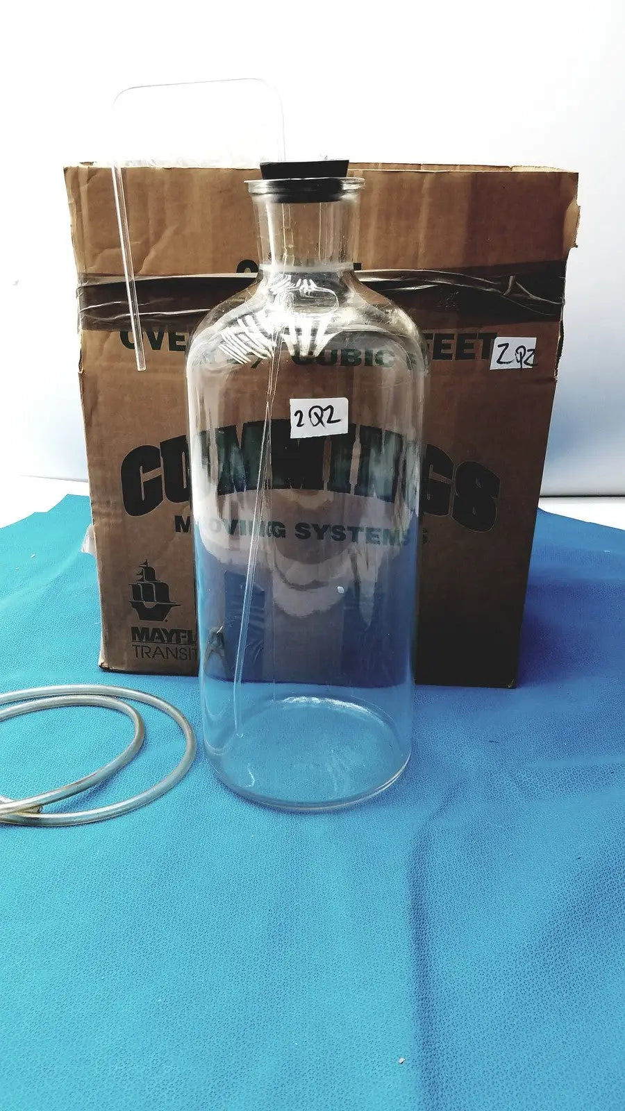 Vintage 9 inch clear glass bottle with black cork stopper and embossed coming lettering, timeless decorative piece