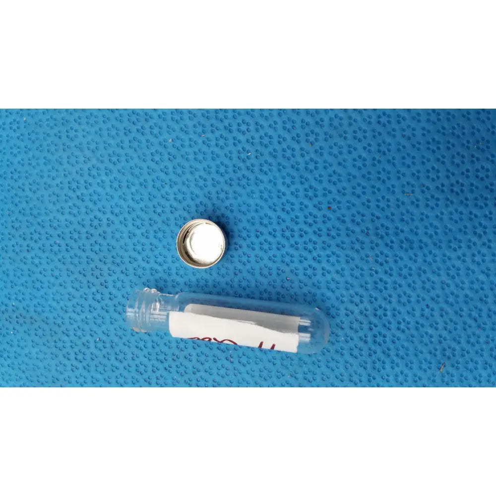 Clear glass vial with silver cap and white label containing vintage johnson new era dental floss in original glass bottle