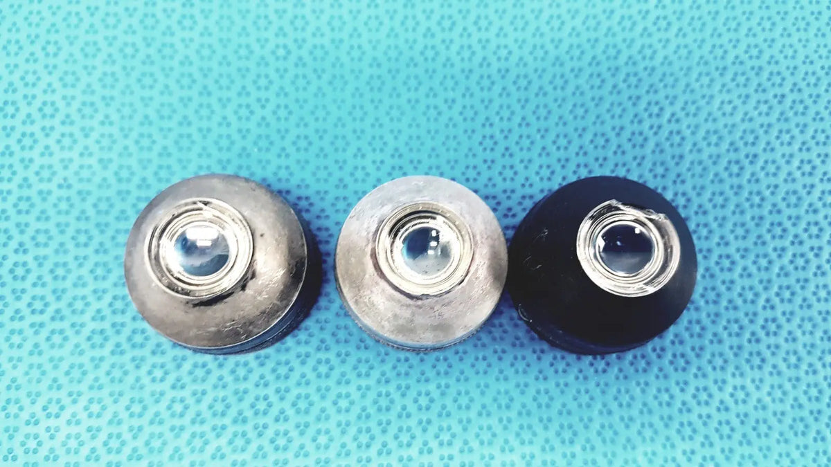 Three volk super quad ophthalmic laser lenses with metallic silver and black finishes featuring central glass elements