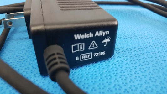 Welch allyn 73305 6v power adapter plug with textured plastic casing and coiled black cord for medical devices