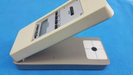 Beige plastic battery operated x-rite 331 transmission densitometer with digital caliper and gray base for precision measuring