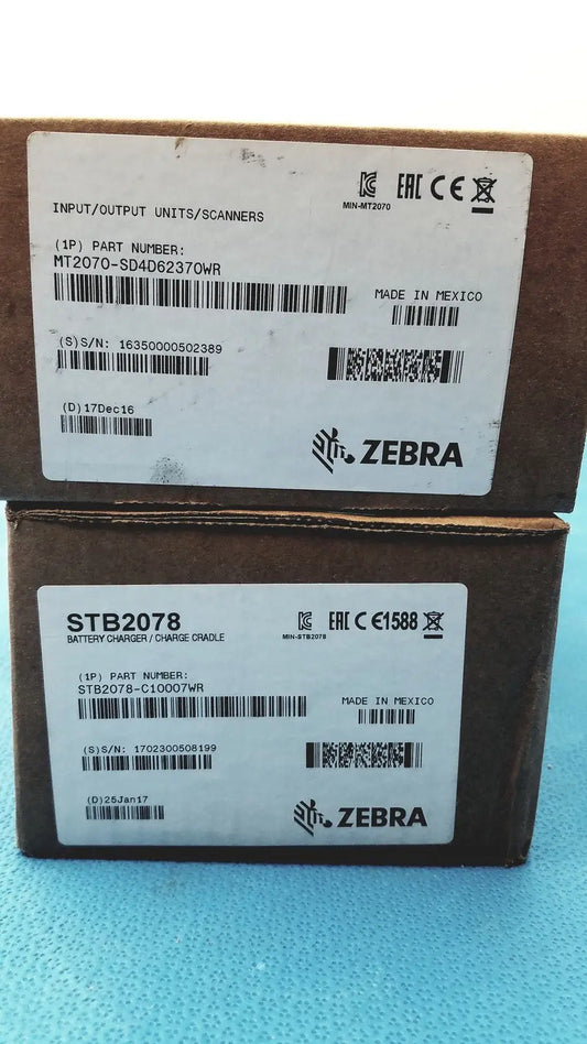Brown cardboard boxes labeled zebra brand and part numbers for mt2070-sd4d62370wr zebra barcode scanner with battery charger