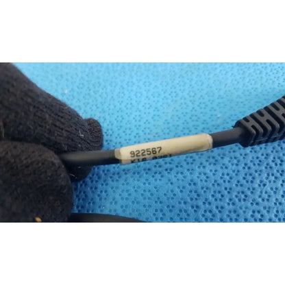 Gloved hand holding black cable with beige label 922567 for 09840-804 barcode scanner pen with rj connector against blue background