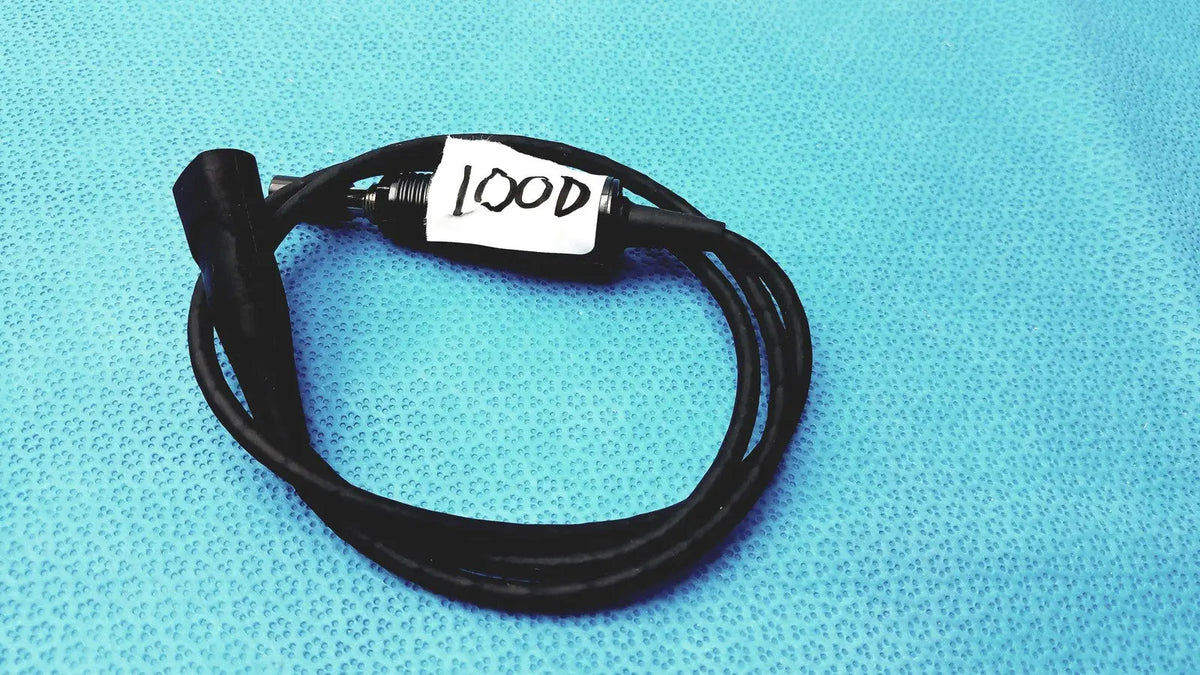 Black coiled 100cm smartwatch charging cable with metallic connector and safety protection features labeled lood