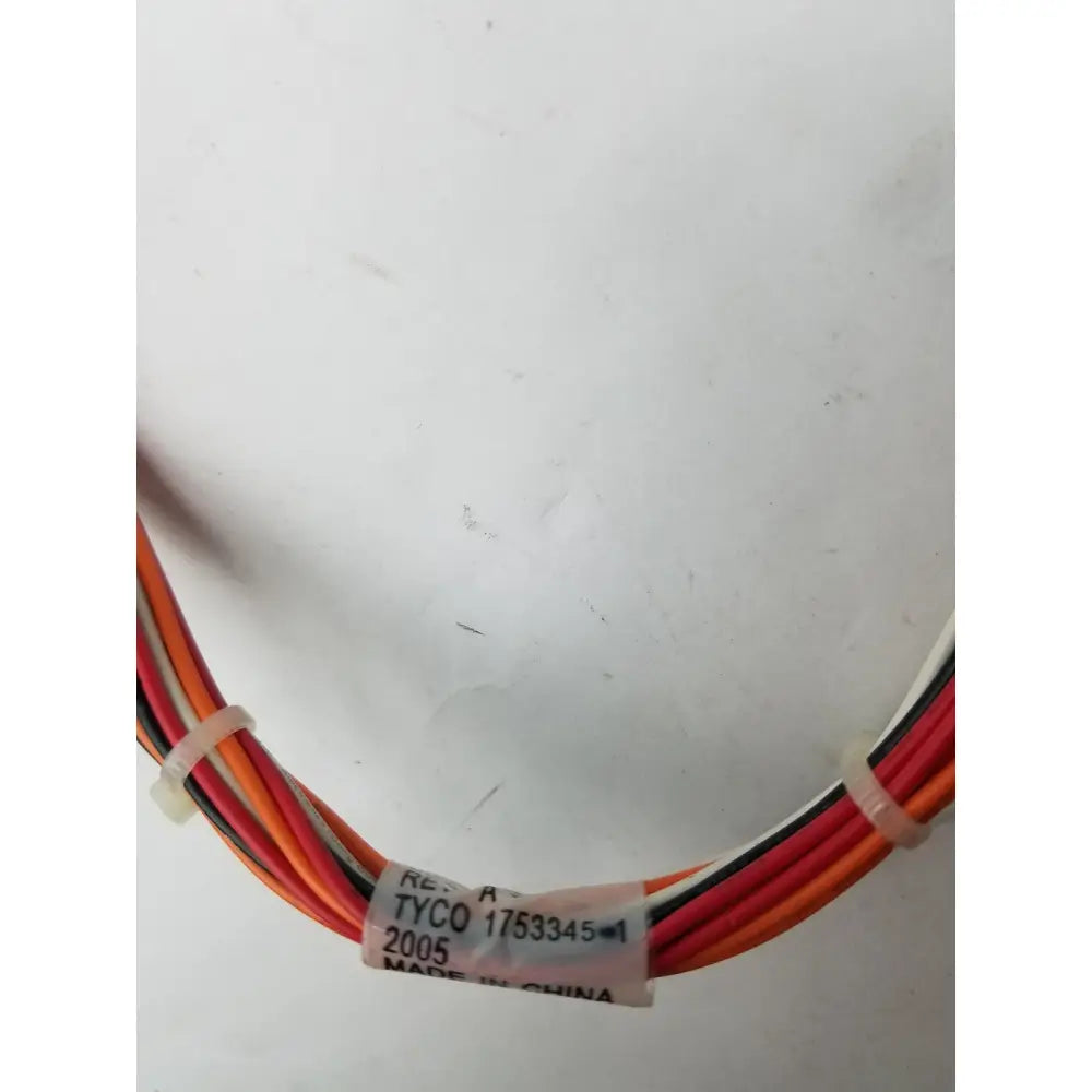 A bundle of multi-colored electrical wires neatly tied with clear plastic ties and labeled with a tyco pin female connector tag
