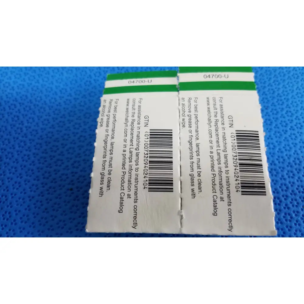 White paper label with green border and black barcode showing product id and care instructions for welch allyn 04700-u replacement lamp bulb pack
