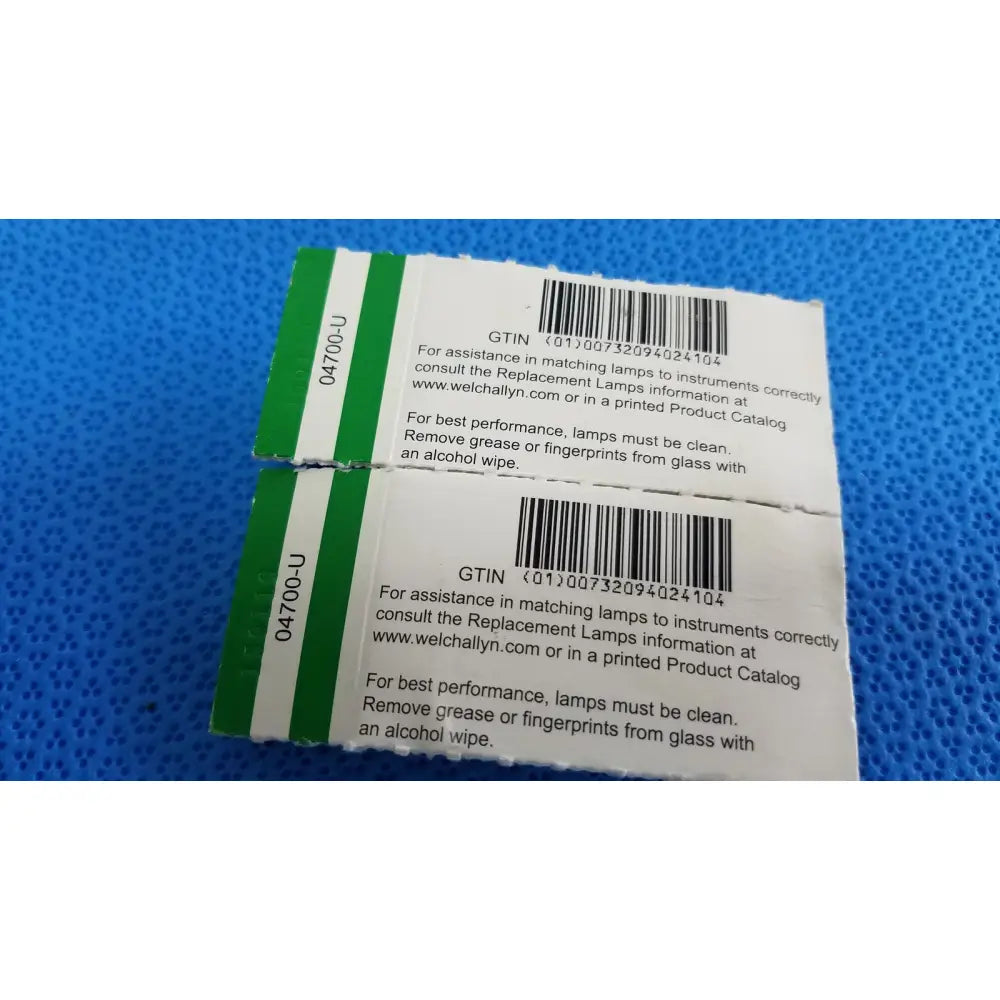 Two white and green welch allyn 04700-u replacement lamp bulb labels with barcode and instructions for lamp replacement