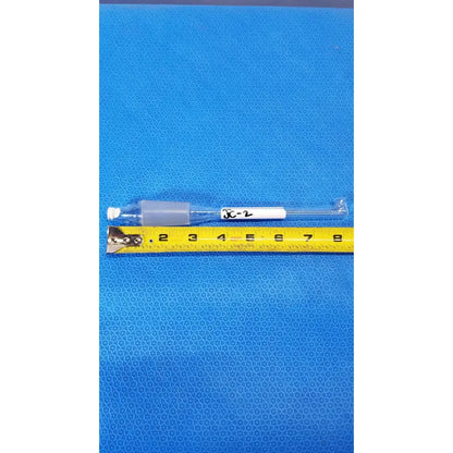 Clear glass thermometer adapter with gray plastic tip and white label xc-2 next to yellow measuring tape for lab thermometry use