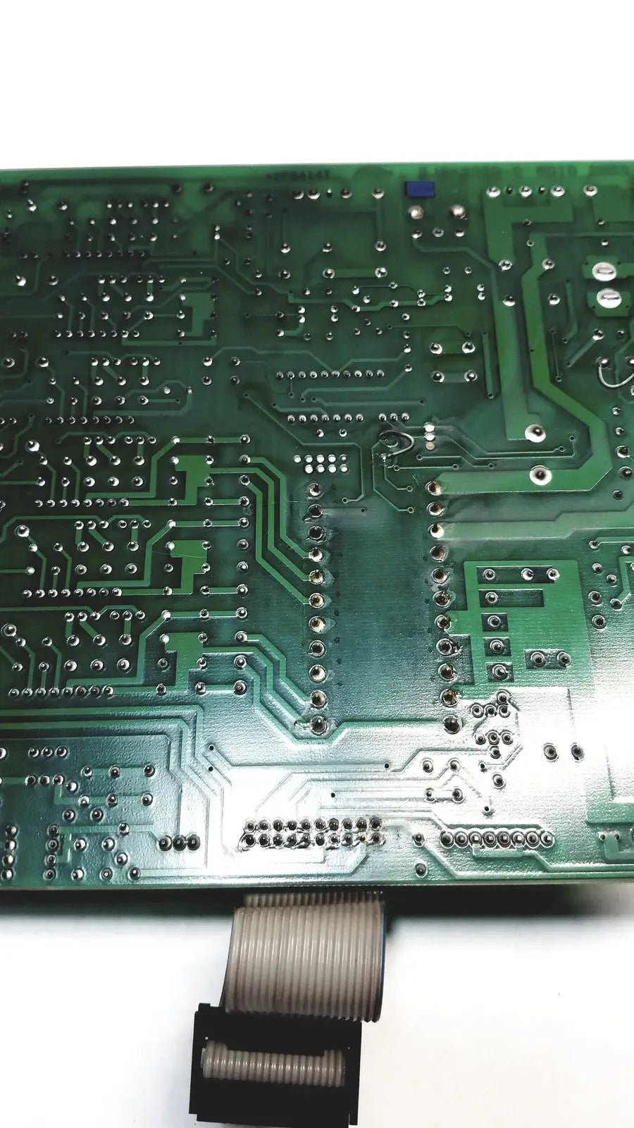 Green printed circuit board with silver soldered components and flexible ribbon cable connector on 2p8414t mother board
