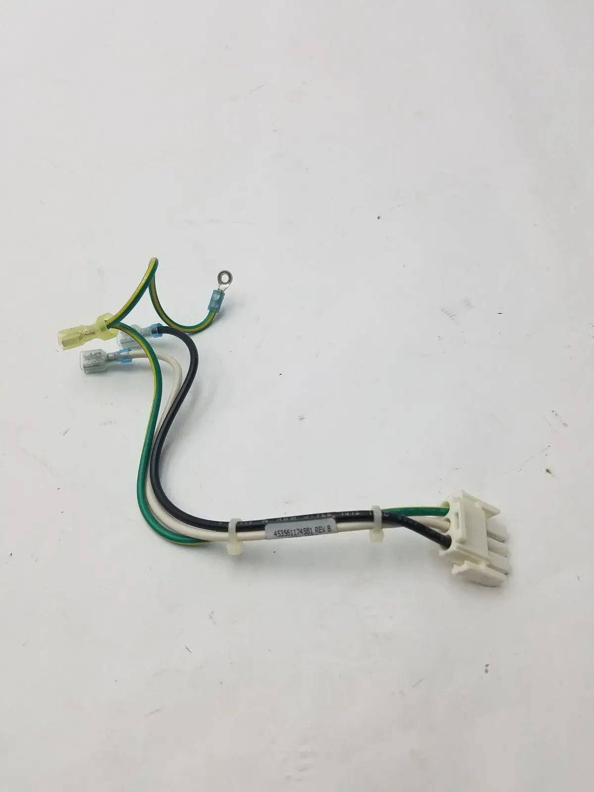 A white plastic 3 pin female connector with green, black, and yellow wires and a label attached to the bundle