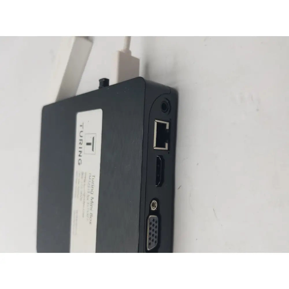 Black mini box showing backside with multiple ports including ethernet hdmi and vga featuring a pin female connector cable