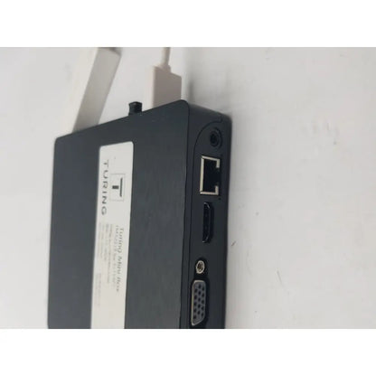Black mini box showing backside with multiple ports including ethernet hdmi and vga featuring a pin female connector cable