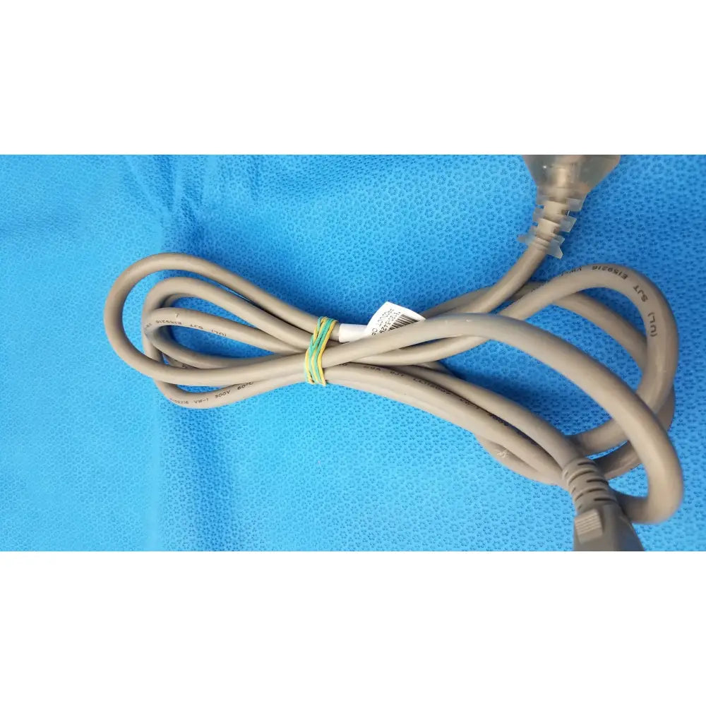 A beige 3-prong power cable standard ac cord with plastic plug and label secured by green and yellow tie