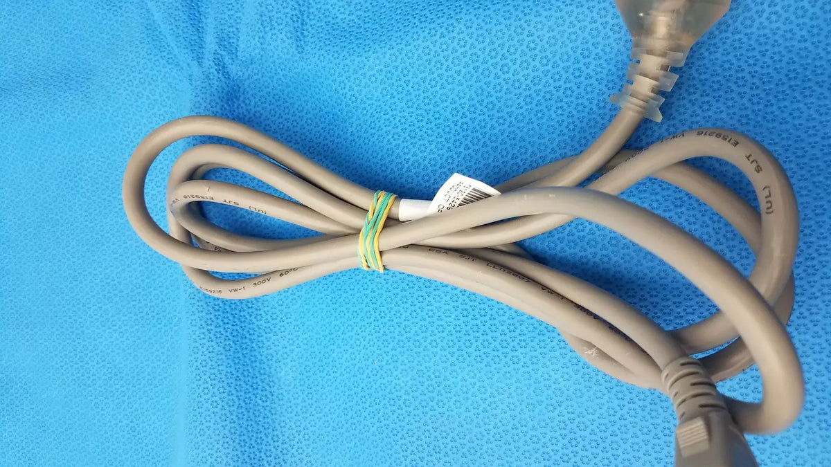 A beige 3-prong power cable standard ac cord with plastic plug and label secured by green and yellow tie