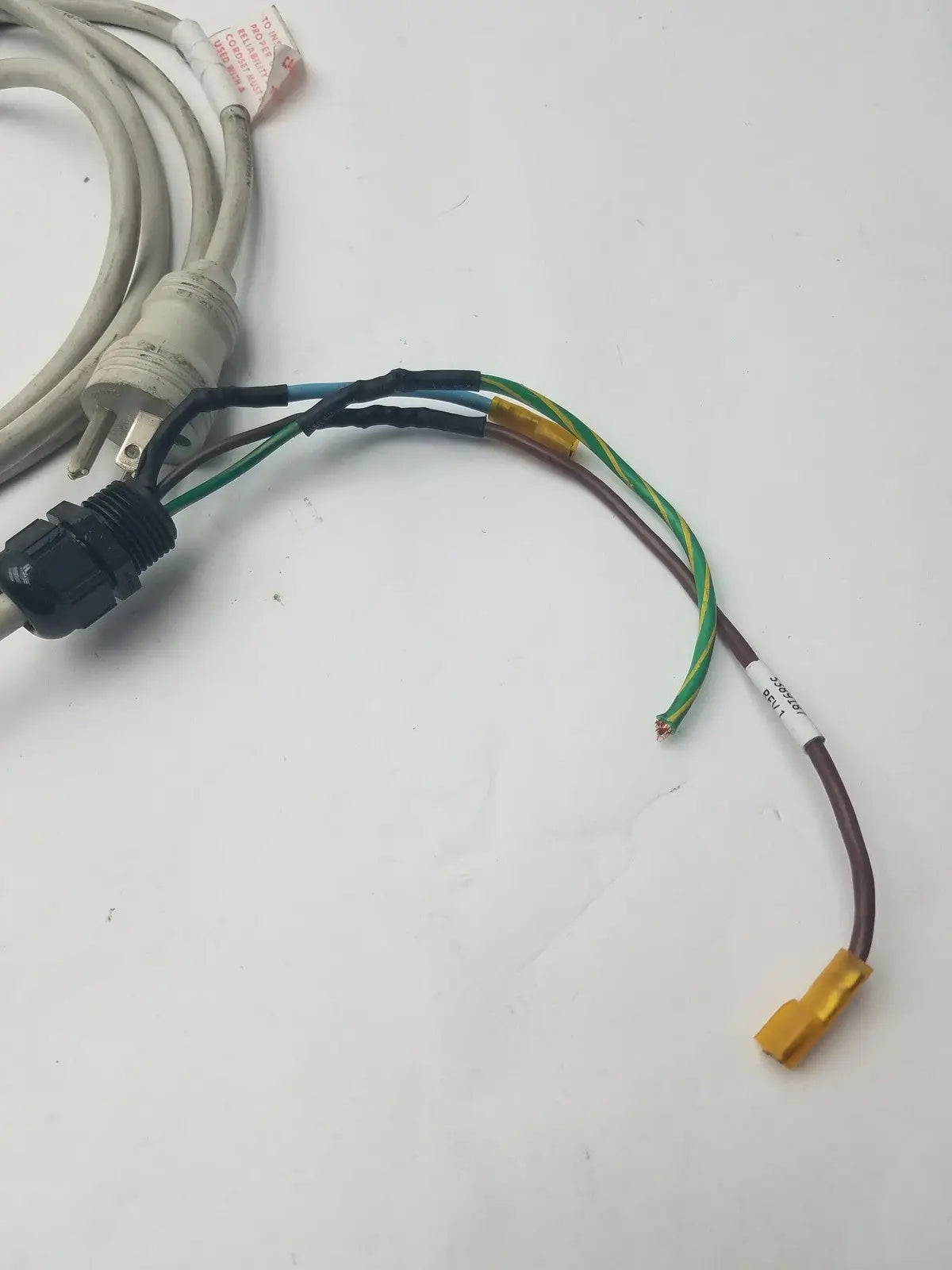 A coiled beige 3 prong power cable with a black wire connector harness and multiple colored wires extending from it