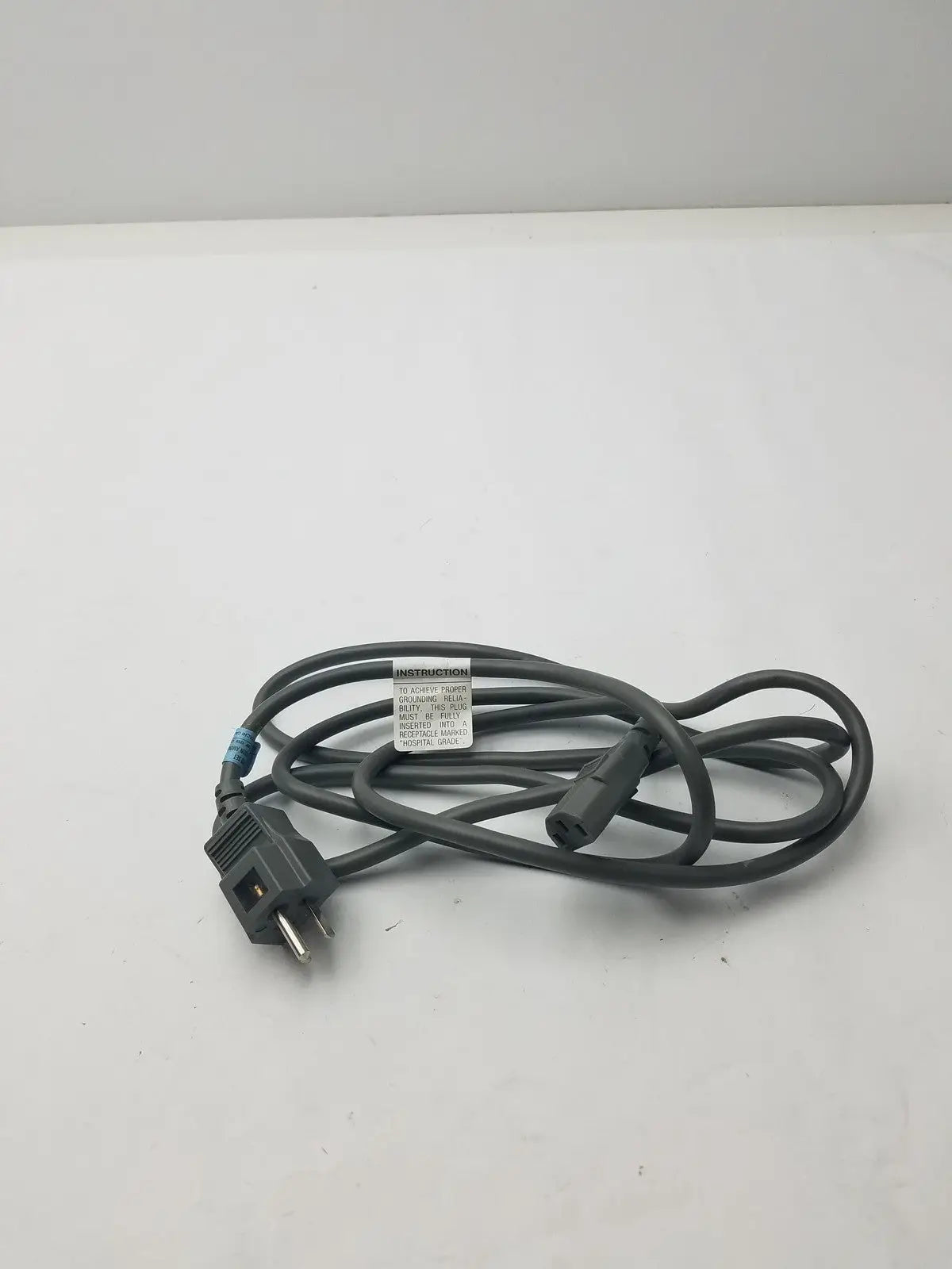 Black 3 prong power cord detachable cable with two-prong plug, three-prong connector, and instruction label wrapped around middle