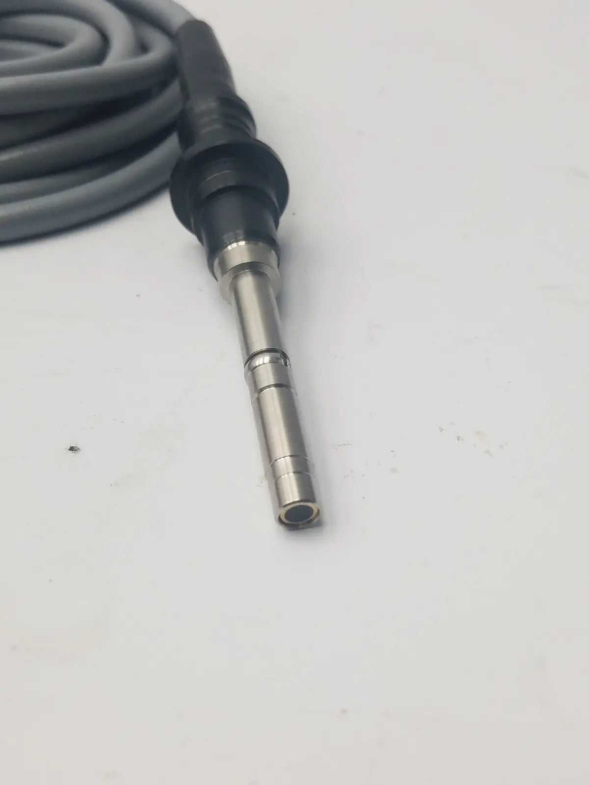 Gray fiber optic light guide cable coiled with black and metallic connector for precise light transmission
