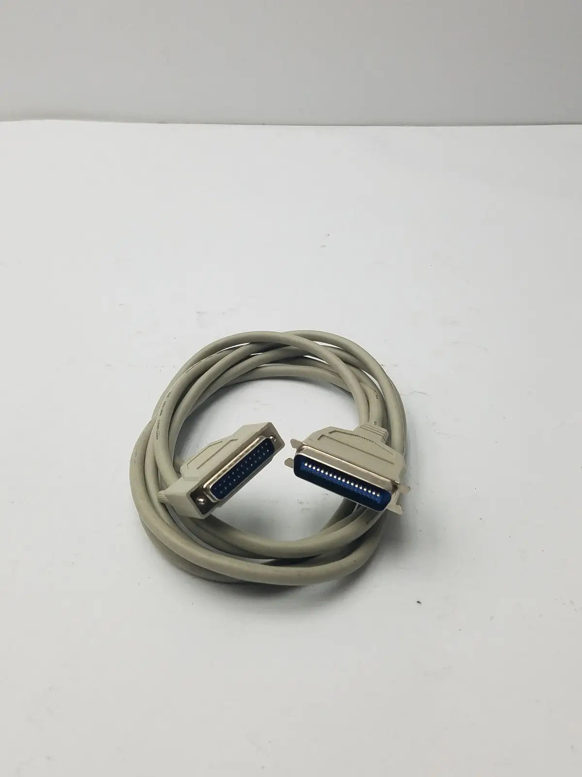 Beige coiled 36-pin male to 25-pin male parallel printer cable with metallic connectors and blue internal contacts