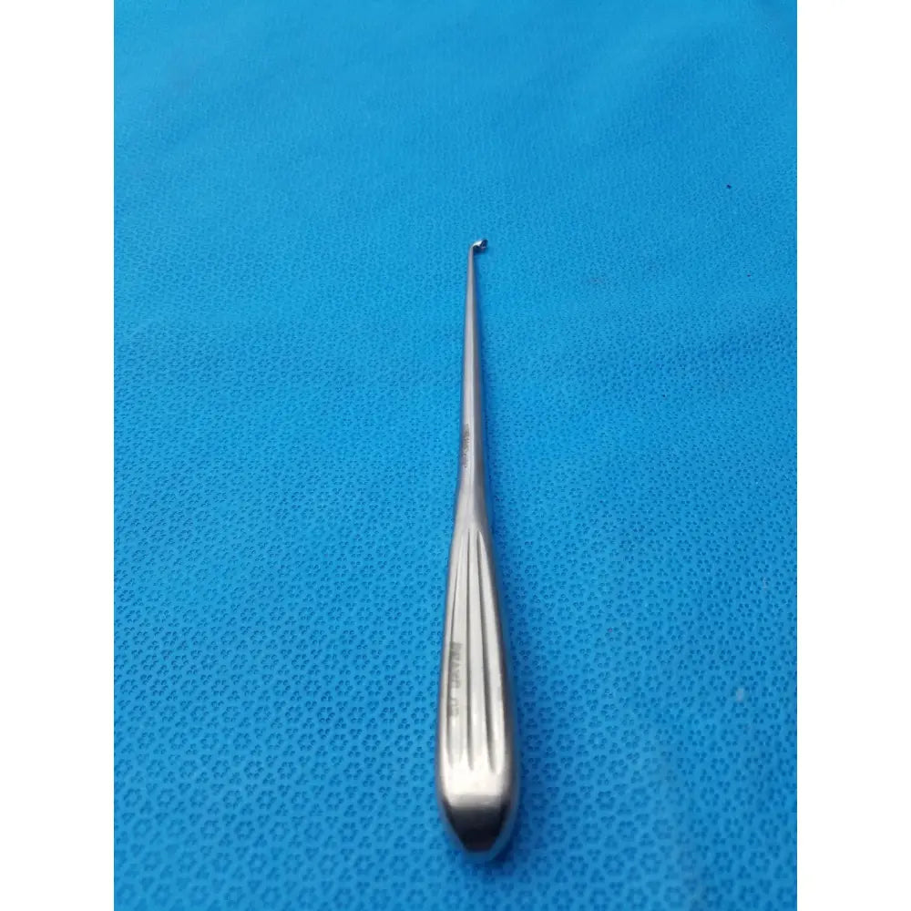 A sleek stainless steel spratt bone curette with vertical grooves and a fine curved tip for orthopedic use