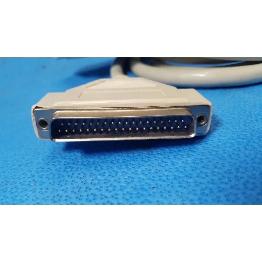 White plastic-to-metal 25 pin male db25 connector with gold-plated pins attached to a coiled gray female connector cable