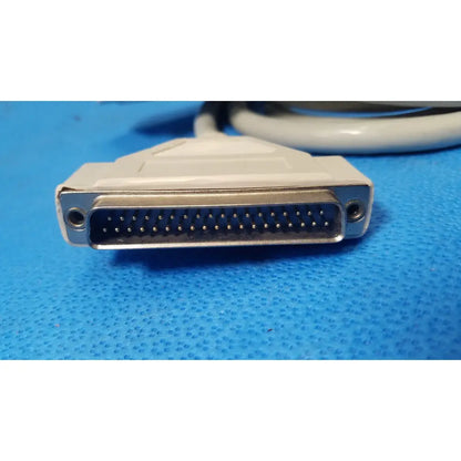 White plastic-to-metal 25 pin male db25 connector with gold-plated pins attached to a coiled gray female connector cable
