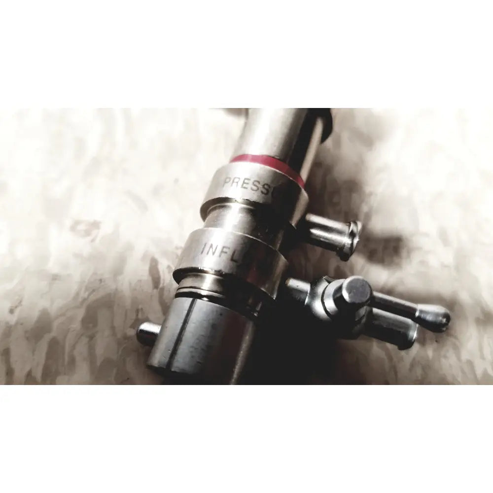 Silver metallic 3M 83272 pressure dispensing cannula with engraved press and infl markings and red rubber band