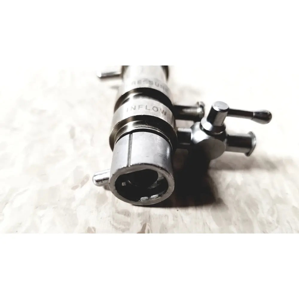 Silver metallic 3M 83272 pressure dispensing cannula with engraved inflow label and dual rotating stopcock knobs
