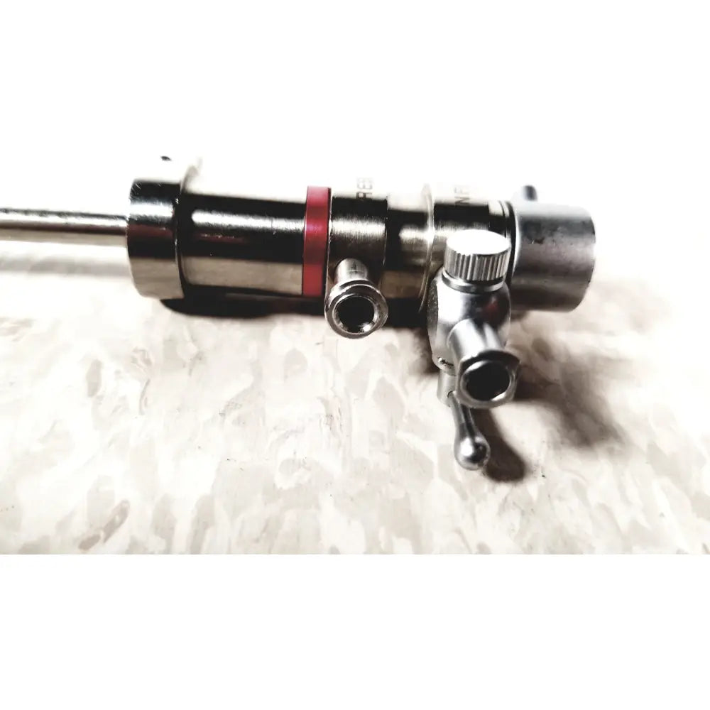 Silver pressure dispensing cannula with red band and multiple ports featuring rotating stopcocks for precise dispensing