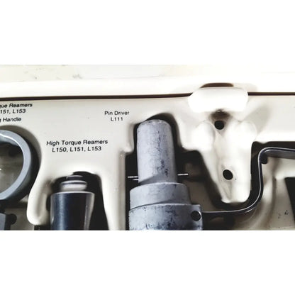 Gray metallic pin driver model l111 placed in white plastic tool tray of 3M driver ii autoclave tray air powered set