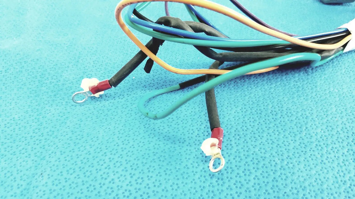 A bundle of multi-colored insulated connector wire harness cables with red terminals and metal loop ends