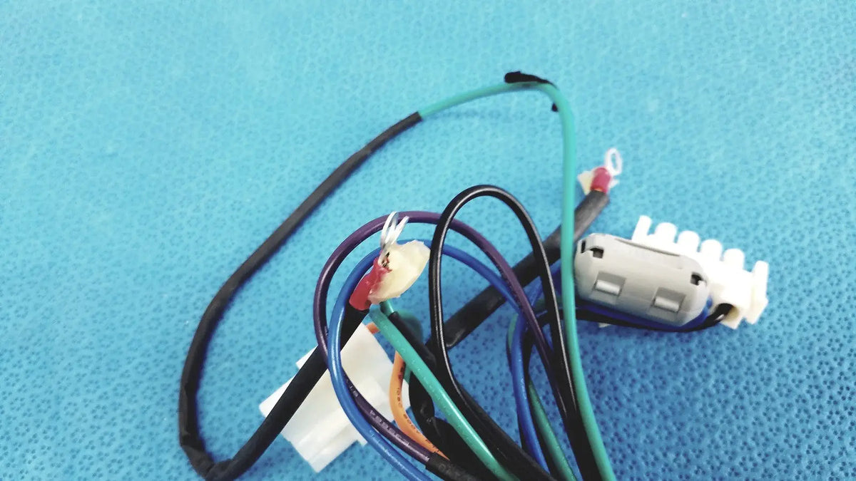 A tangle of multi-colored wires with a white plastic connector in a 4 multi-pin connector wire harness cables