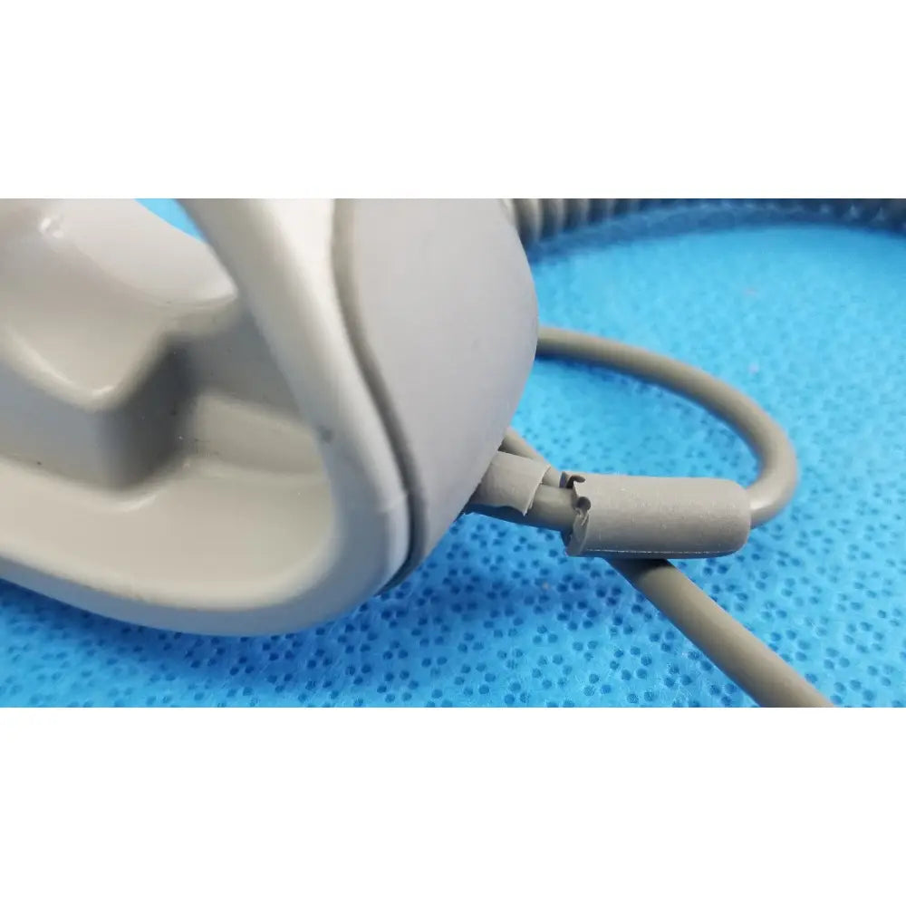 Gray plastic remote control headset with coiled cord and cracked connector for patient lift chair use