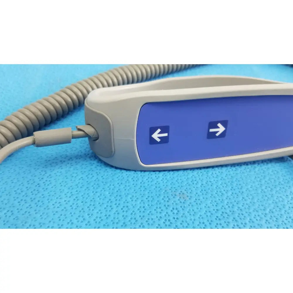 Gray and blue remote control with directional arrows on coiled cord for patient lift chair 700-13865 functions