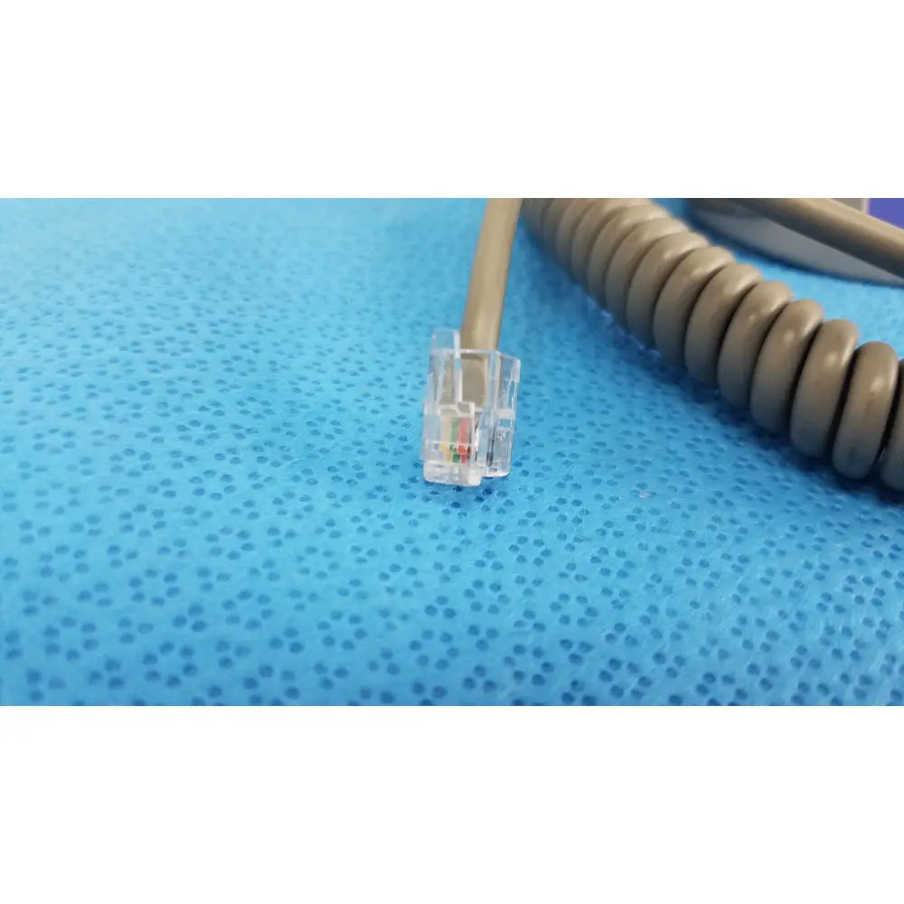 Clear plastic rj45 ethernet connector with colored wires on beige coiled cable for patient lift chair remote control