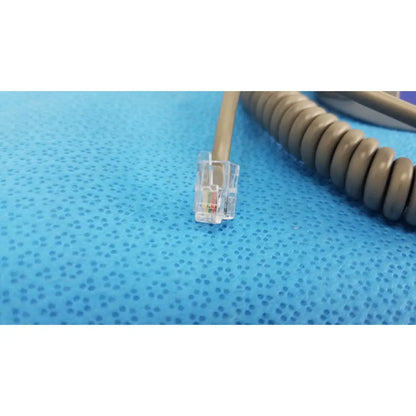 Clear plastic rj45 ethernet connector with colored wires on beige coiled cable for patient lift chair remote control