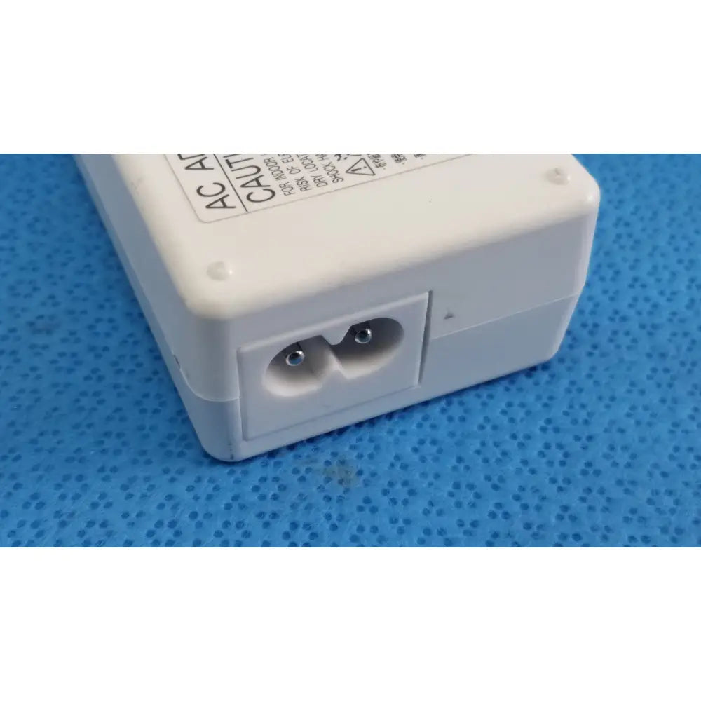 White plastic ac power adapter sed80n2-24 with two round pin sockets and caution label on top surface