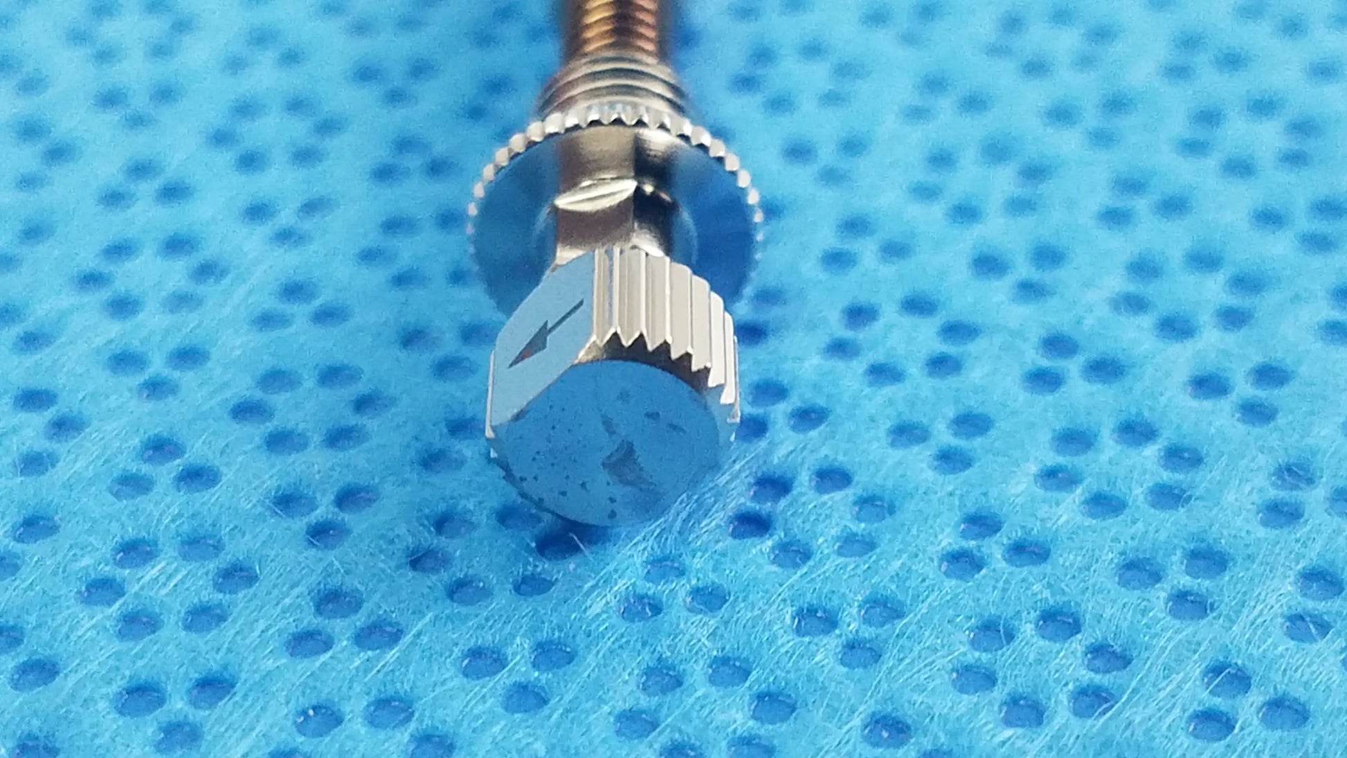 Silver-toned watch crown with hexagonal textured head and ridged edges featured in ace 765-1001 sterilization tray dental implant kit