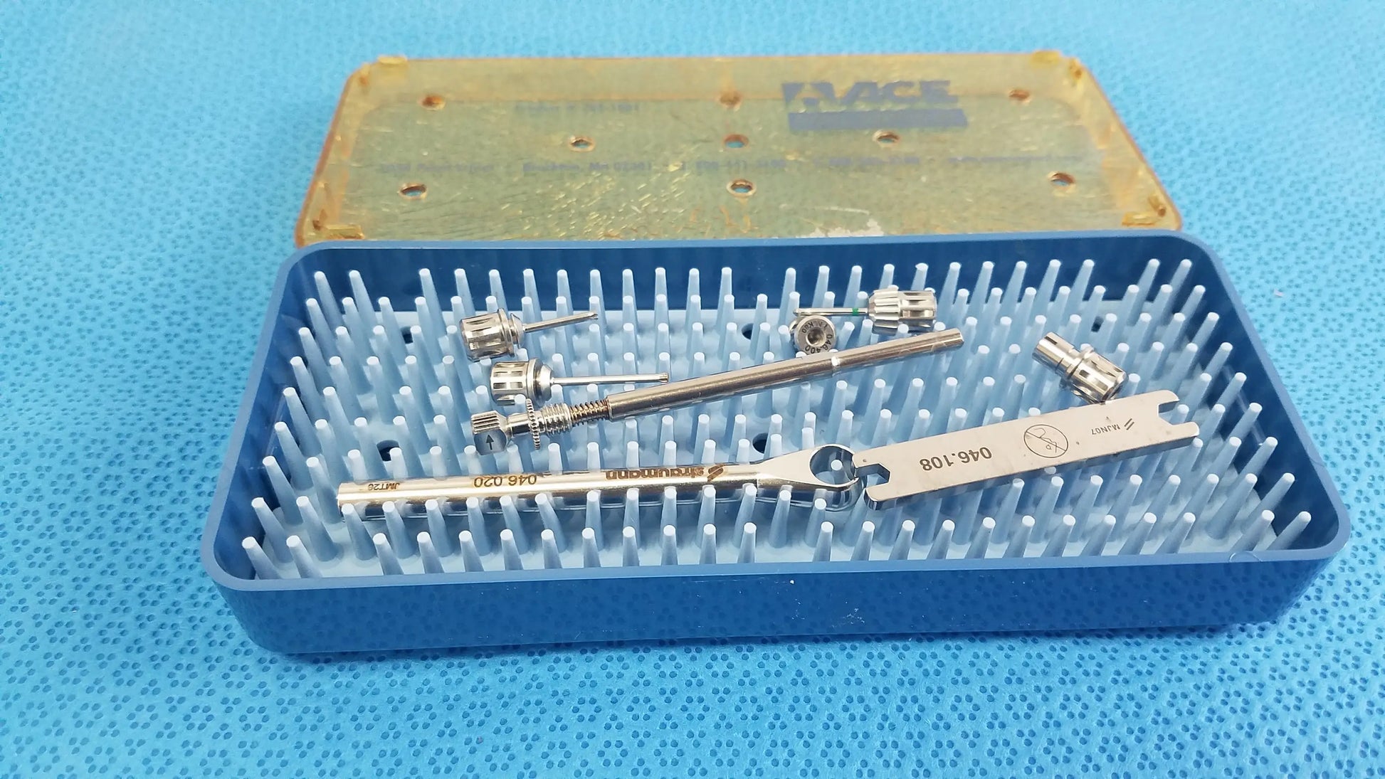 Ace 765-1001 sterilization tray with silver metal dental implant tools and clear plastic lid for medical equipment use