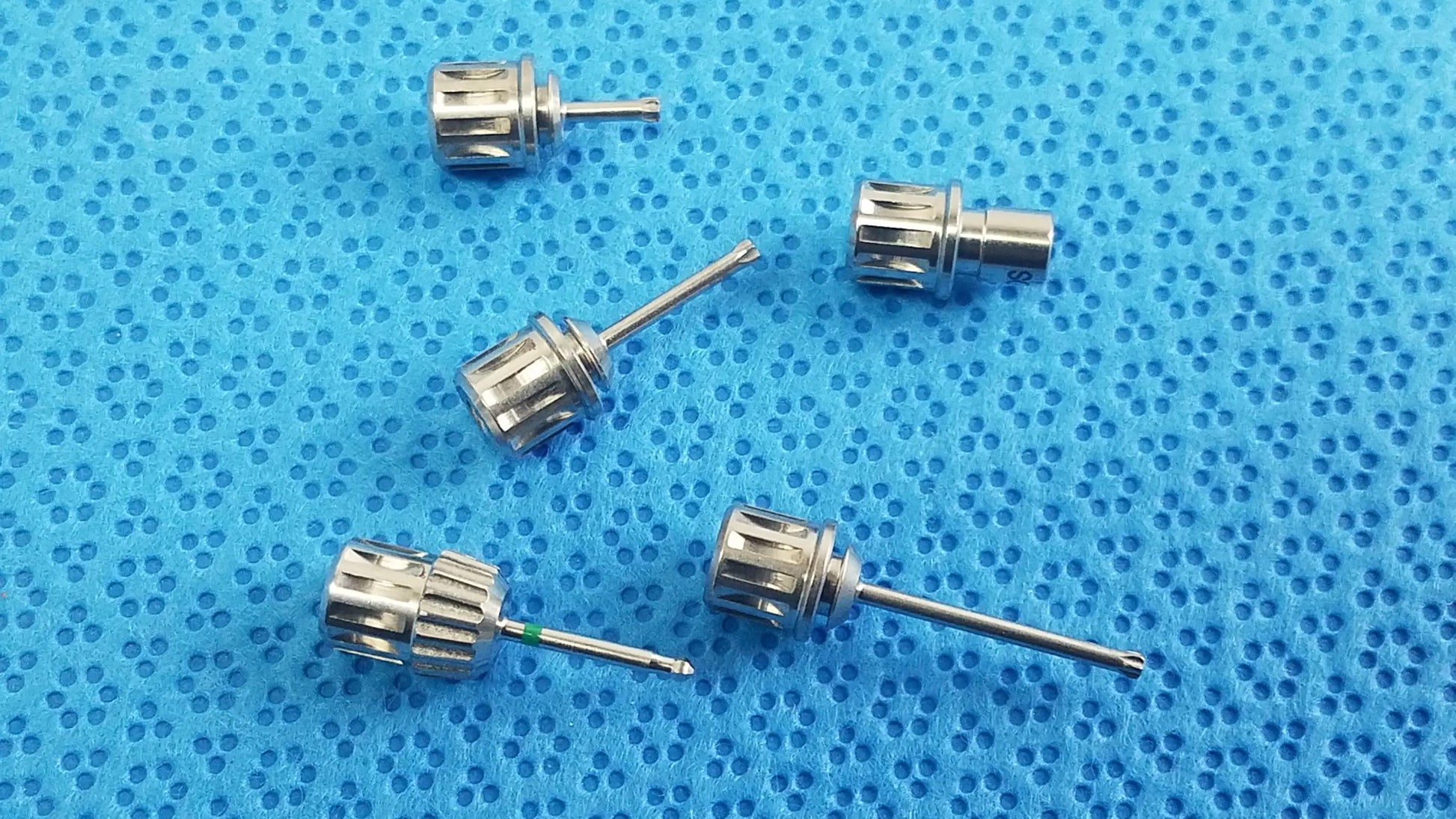 Silver-colored metal watch crown adjusters with textured gear-like surface and slender stems in ace 765-1001 sterilization tray for dental implant medical equipment