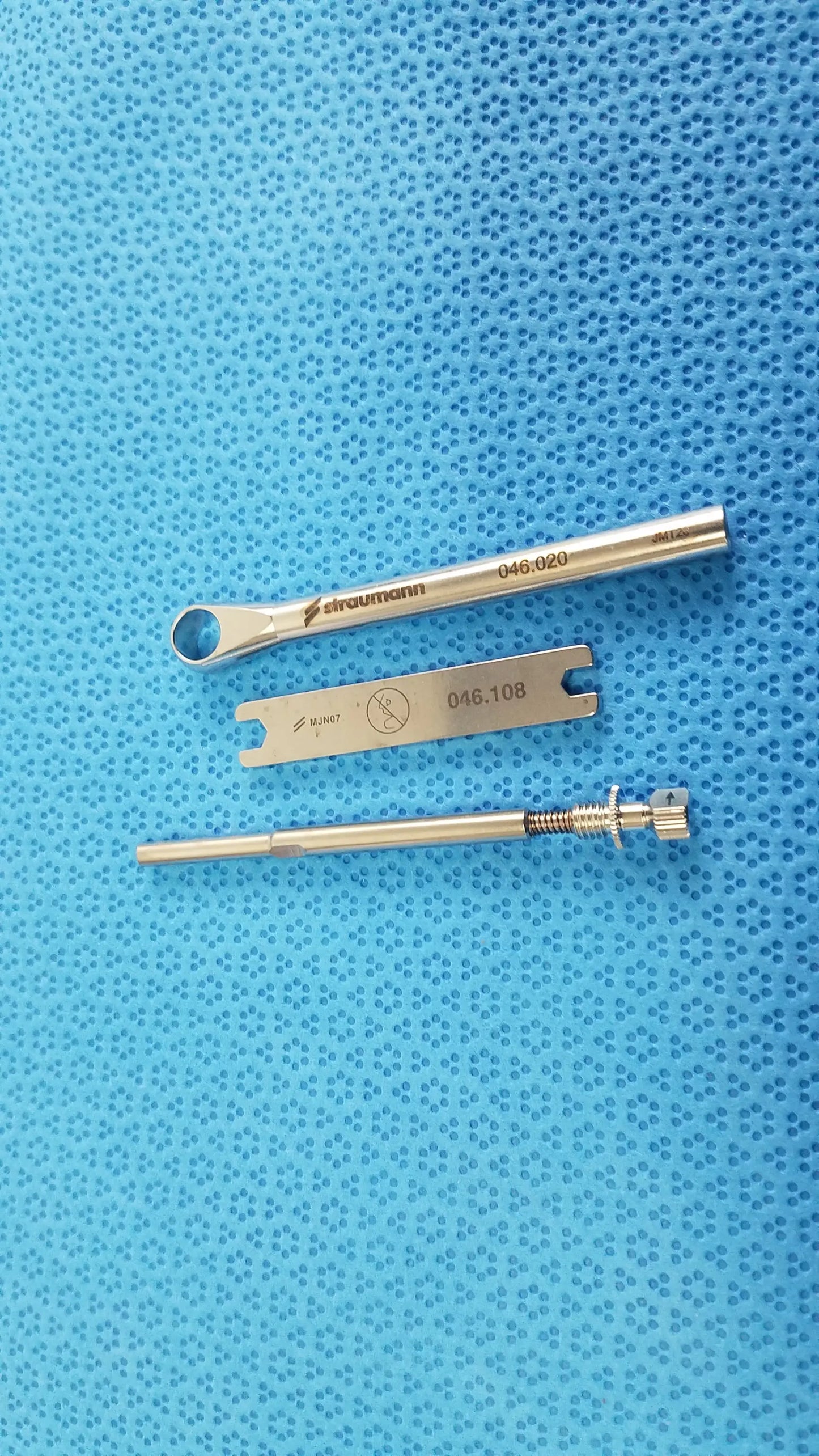 Silver-colored Straumann dental implant screw with threaded shaft and hexagonal head in ACE 765-1001 sterilization tray medical equipment kit