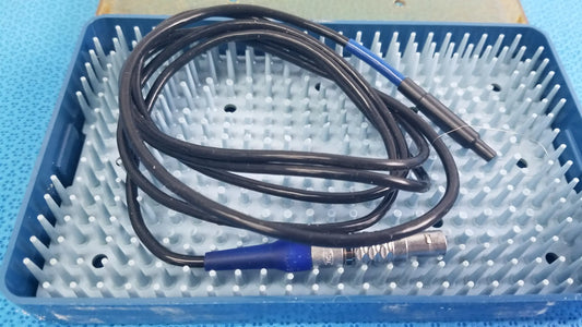 Black coiled cable with blue connectors and metallic end resting in blue sterilization tray for multigen radiofrequency probe