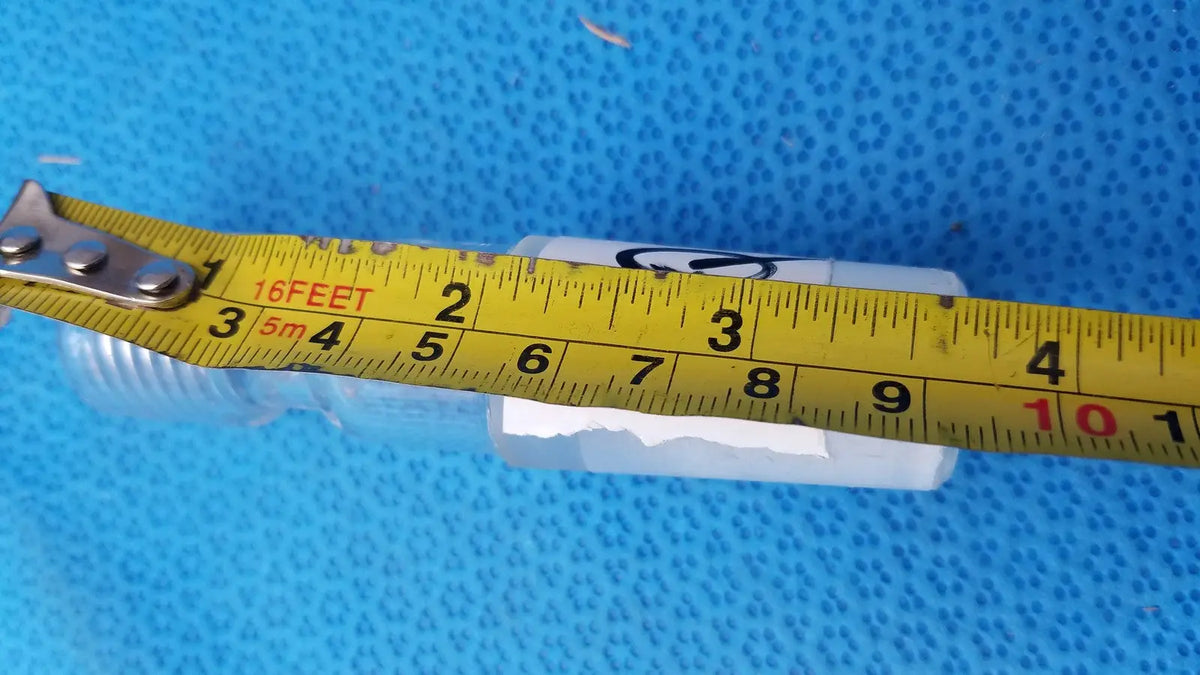 White plastic ace glass ace-thred thermometer adapter with threaded ends and a yellow measuring tape across it