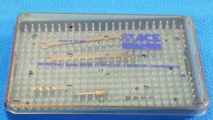Clear plastic surgical instrument tray containing gold-colored wrenches and metallic tools for reuse medical equipment