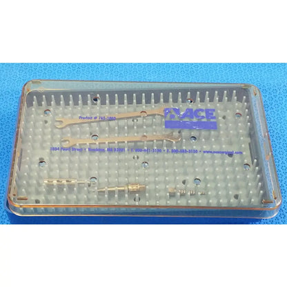 Clear plastic surgical instrument tray containing gold-colored wrenches and metallic tools for reuse medical equipment