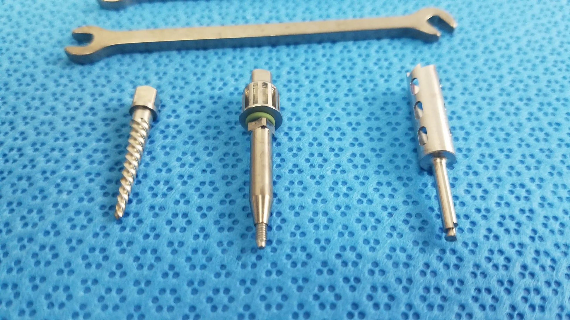 Silver surgical drill bits and wrench on blue textured surface for ace ophthalmology micro surgery medical equipment