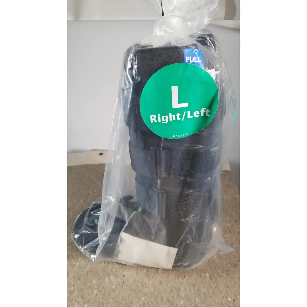 Black adjustable ankle brace in clear plastic packaging with green left right label for actimove standard walker boot achilles