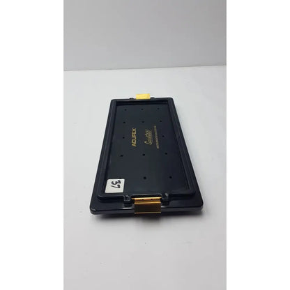 Black plastic acufex suretac instrument camera lens mount with gold metal accents and yellow tab on top for suretac instrument tray