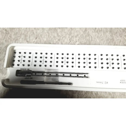 White plastic tray holding surgical drill bits and screws from acumed modular hand system set missing piece