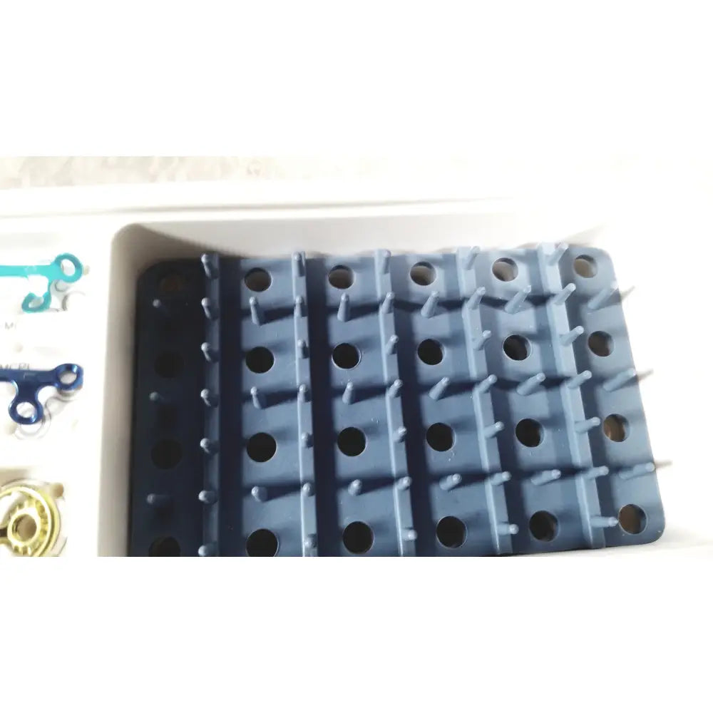 Dark blue plastic pegboard with circular holes and raised pins for acumed modular hand system set missing piece